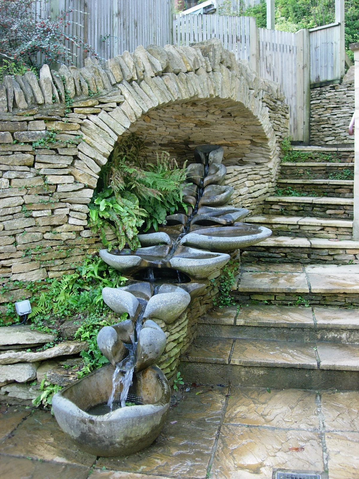 La fontaine Symphonie, avec toutes les Vasques Vives, installée sous une arche de pierres accompagnant la descente d'un escalier.